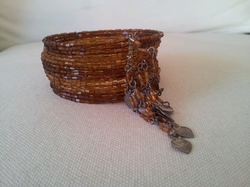 Elegante pulsera en dos tonos de marrón con fleco de detalle metálico.